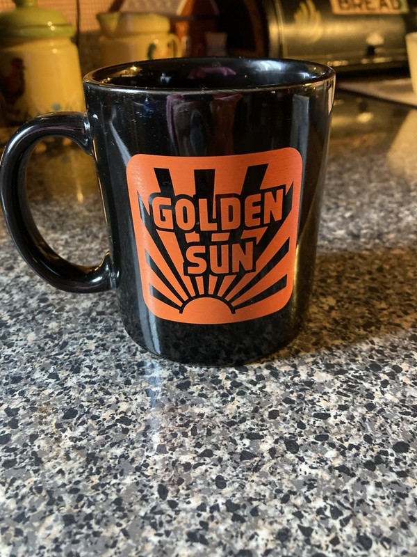Golden Sun Feeds Black Mug Advertising Orange logo